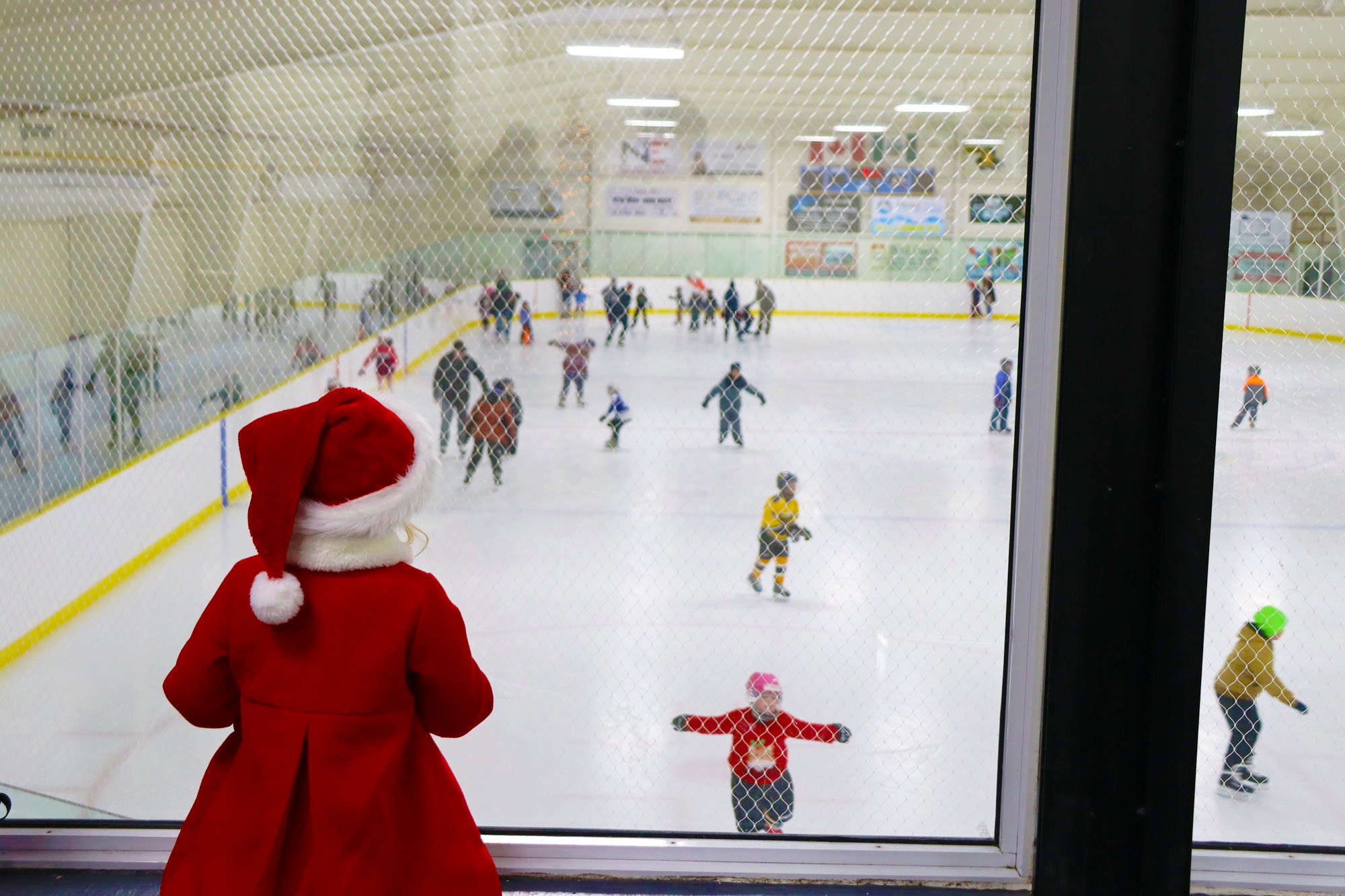 A little girl in a santa suit watching skating